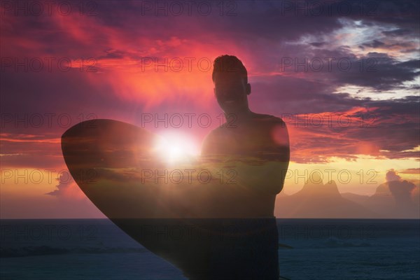 Double exposure of smiling Mixed Race man holding surfboard at beach