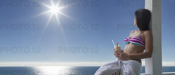 Caucasian woman drinking cocktail at ocean