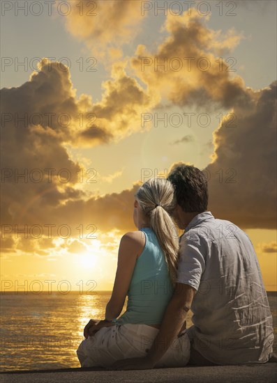 Caucasian couple admiring scenic view of sunset at ocean