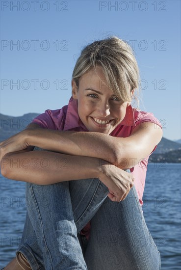 Smiling Caucasian woman sitting near lake