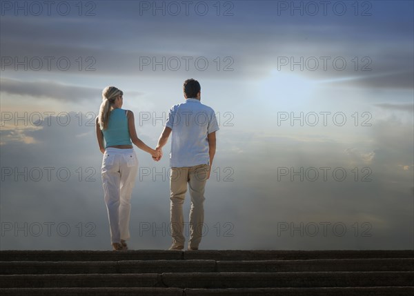 Caucasian couple admiring scenic view of clouds from staircase