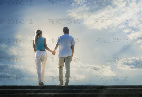 Caucasian couple admiring scenic view of clouds from staircase