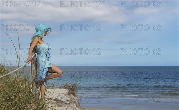 Caucasian woman leaning on wooden post at beach