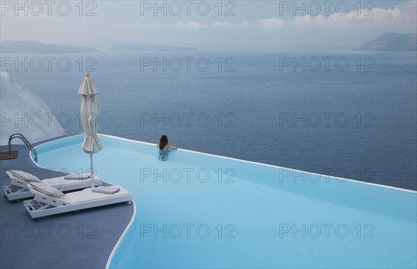 Caucasian woman in infinity pool admiring scenic view of ocean