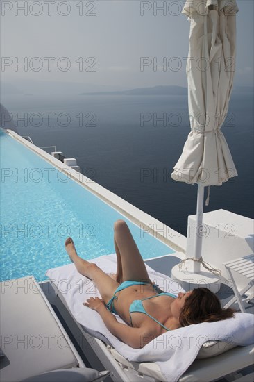 Caucasian woman laying on deck chair near swimming pool