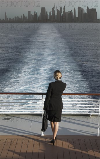 Caucasian businesswoman on boat leaving city