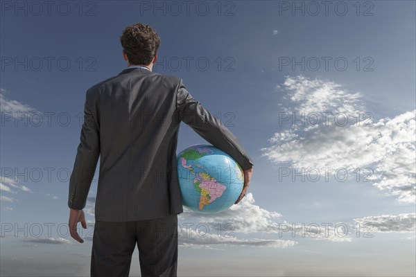 Caucasian businessman holding globe in sky