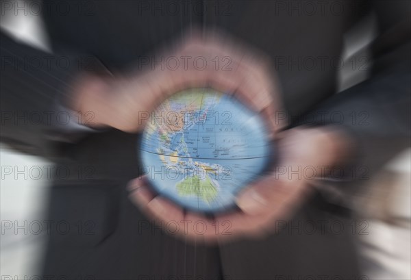 Caucasian businessman holding defocused globe in hands