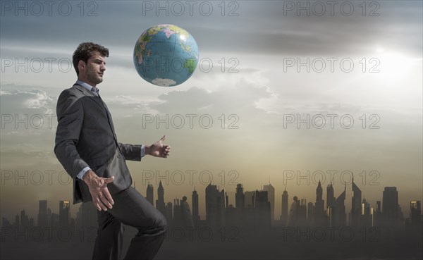 Caucasian businessman juggling globe near city skyline