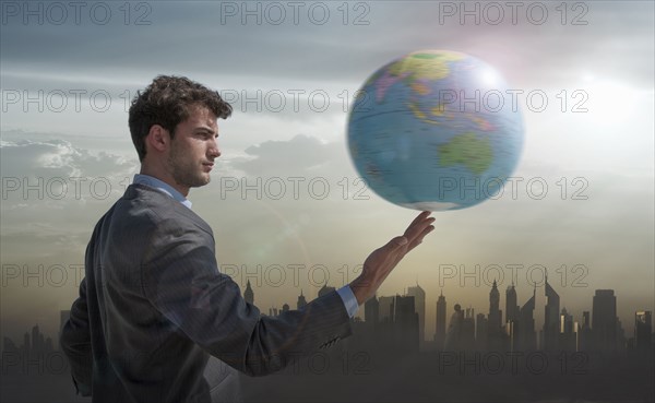 Caucasian businessman spinning globe on finger near city skyline