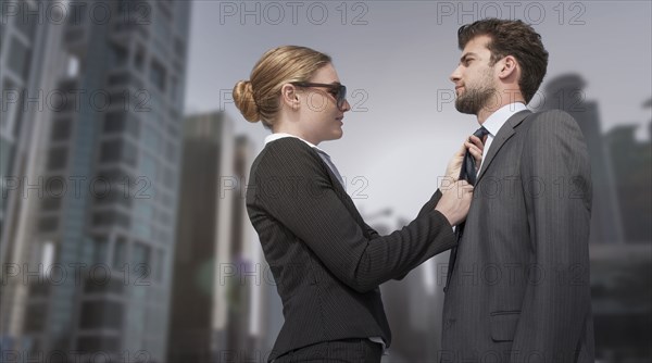 Caucasian businesswoman adjusting necktie for businessman