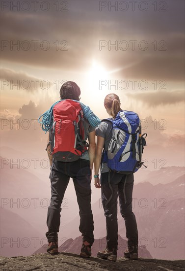 Caucasian hikers on mountain admiring sunset