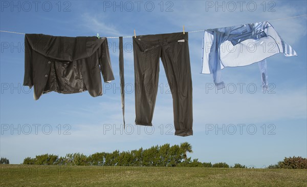 Wet business suit hanging on clothesline in field
