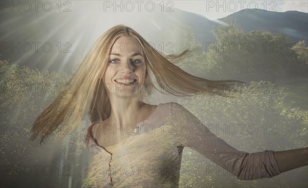 Double exposure of Caucasian woman spinning in forest trees
