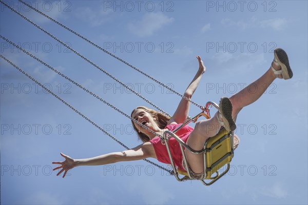 Smiling Caucasian woman riding swing on amusement park ride