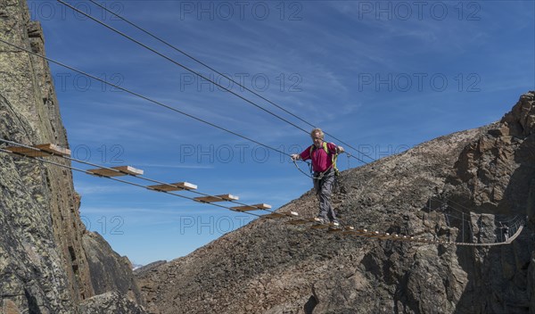 Caucasian man crossing rope bridge on mountain