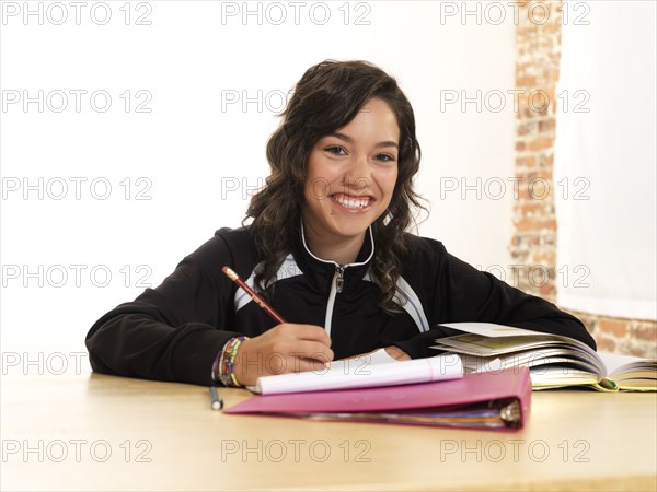 Grinning Hispanic teenager doing homework