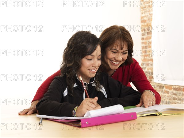 Hispanic mother helping daughter with homework