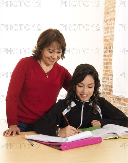 Hispanic mother helping daughter with homework