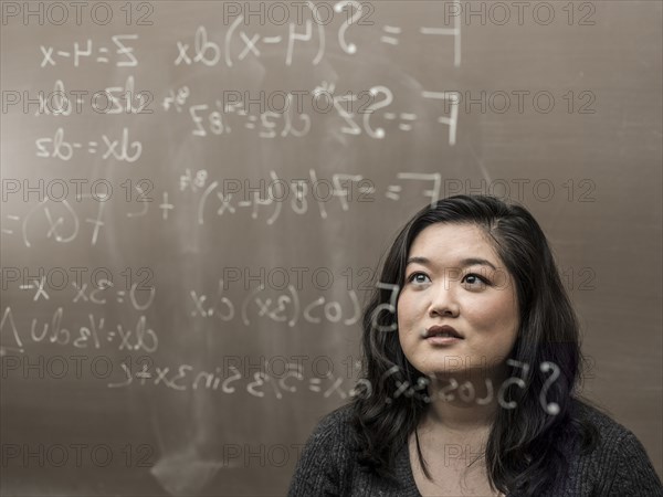 Korean student looking at formula on glass wall