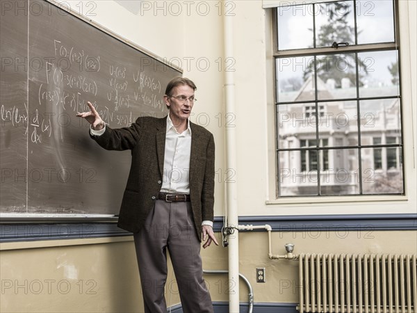 Caucasian teacher writing on blackboard