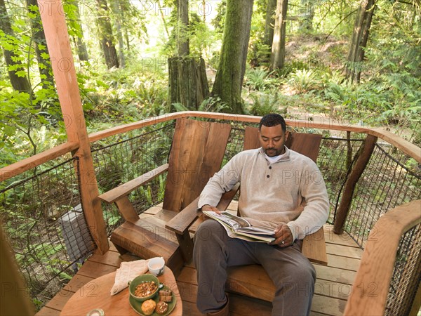 Mixed race man reading book on deck