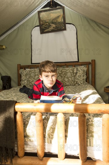 Caucasian boy laying in bed in tent