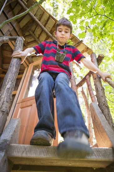 Caucasian boy climbing down from tree house