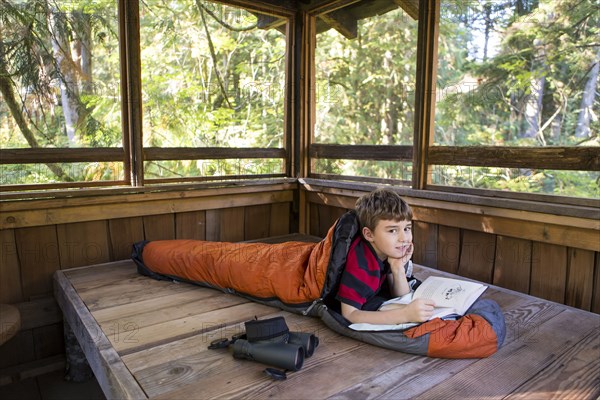 Caucasian boy reading in sleeping bag