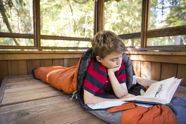 Caucasian boy reading in sleeping bag