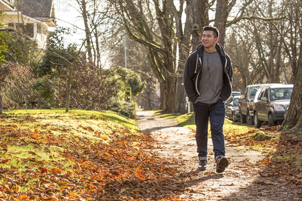 Mixed race man walking on suburban street