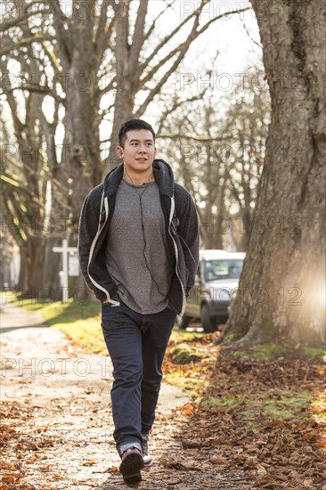 Mixed race man walking on suburban street