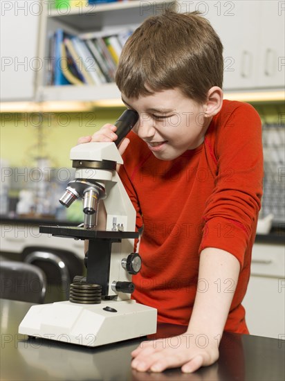 Caucasian boy using microscope in chemistry lab