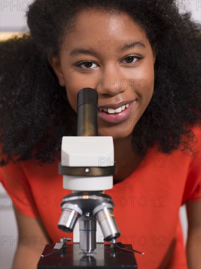 Black girl using microscope in chemistry lab