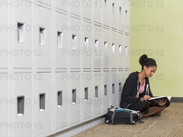 Black student reading in front of lockers