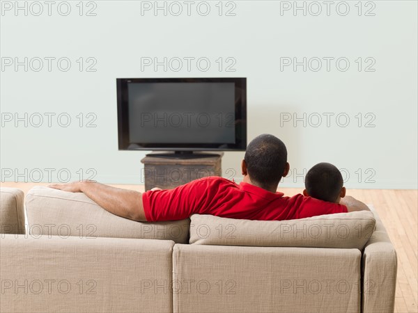 Father and son watching television in living room
