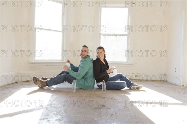 Mixed race couple sitting on floor of new home