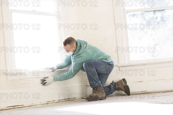 Mixed race carpenter cleaning wall