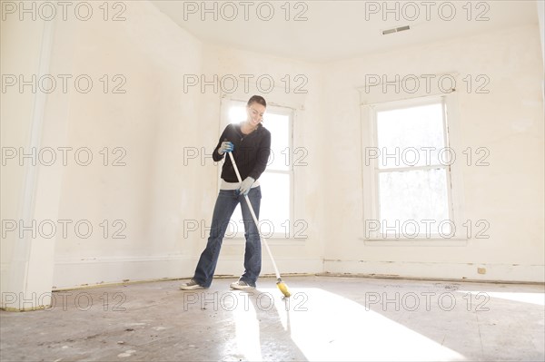 Mixed race woman sweeping floor of new home