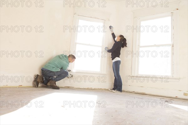 Mixed race couple cleaning wall new home