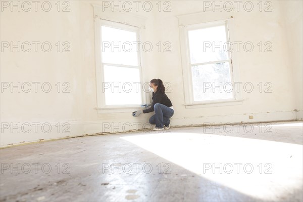 Mixed race woman cleaning wall in new home