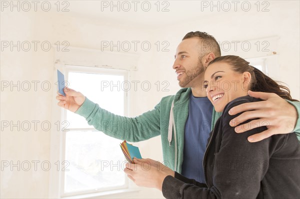 Mixed race couple selecting color swatches in new home