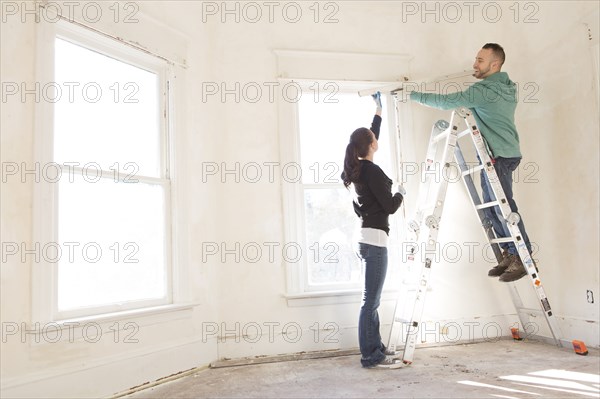 Mixed race couple installing shade in new home