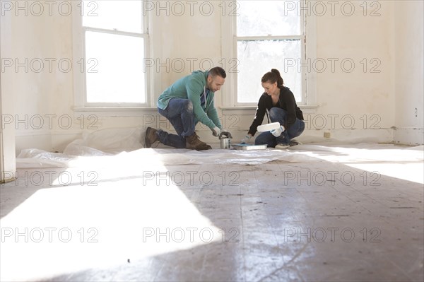 Mixed race couple painting walls of new home