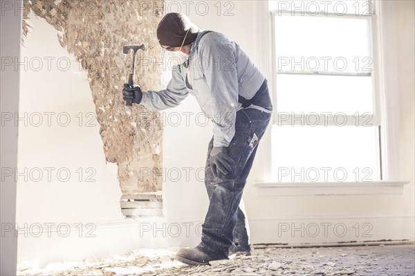 Hispanic construction worker hammering wall