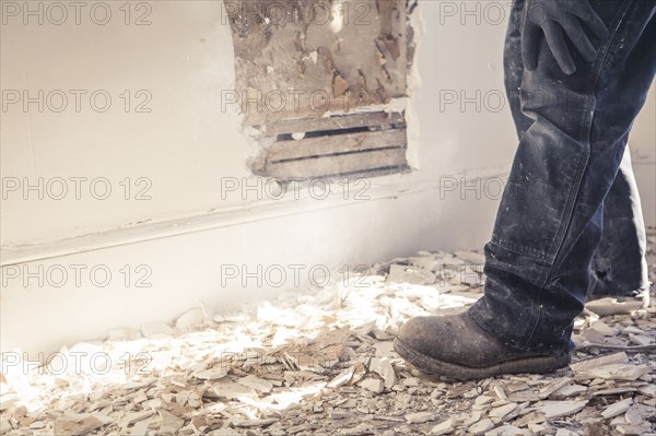 Hispanic construction worker standing in rubble of wall