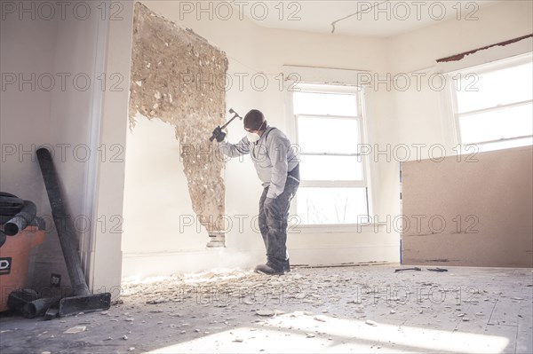 Hispanic construction worker demolishing wall