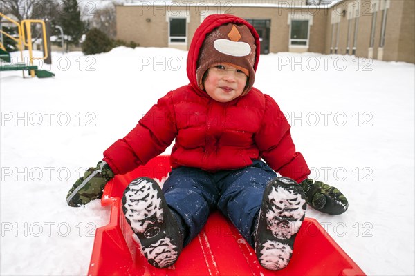 Mixed race boy sitting on sled in snow
