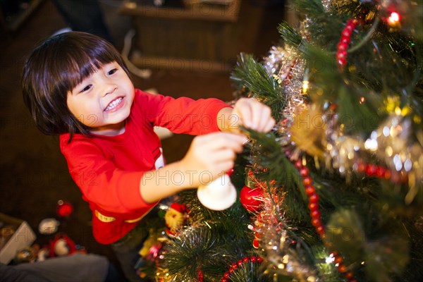 Mixed race girl decorating Christmas tree