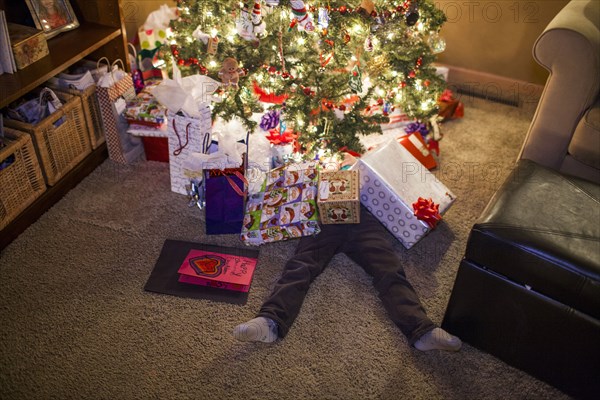 Caucasian boy buried in Christmas gifts